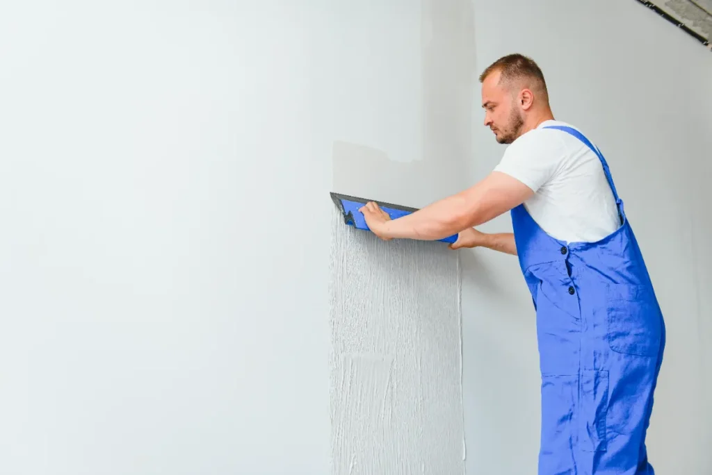 A service worker drywall repairing the walls of the house.