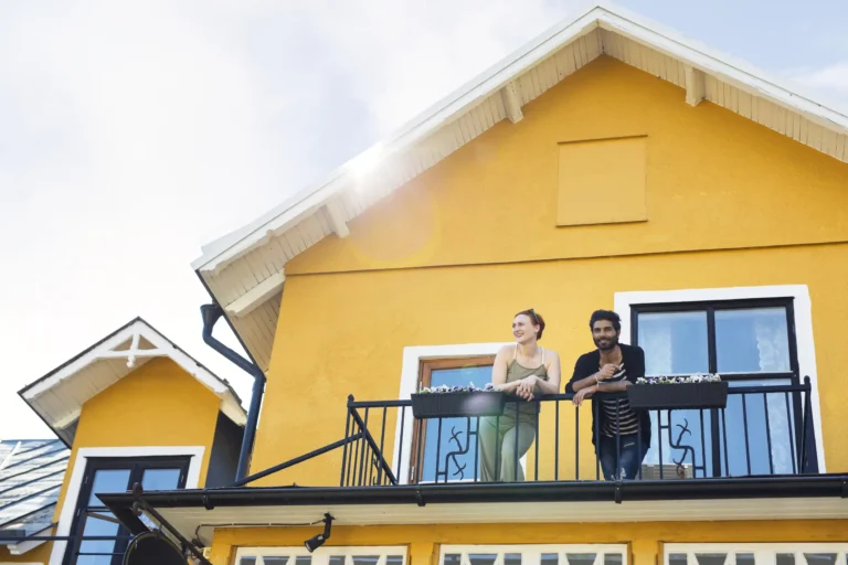 Couple happily gazing from the balcony of their house.