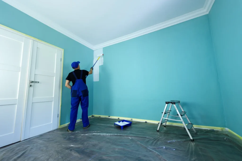 A man starting the white paint in an interior of the home.