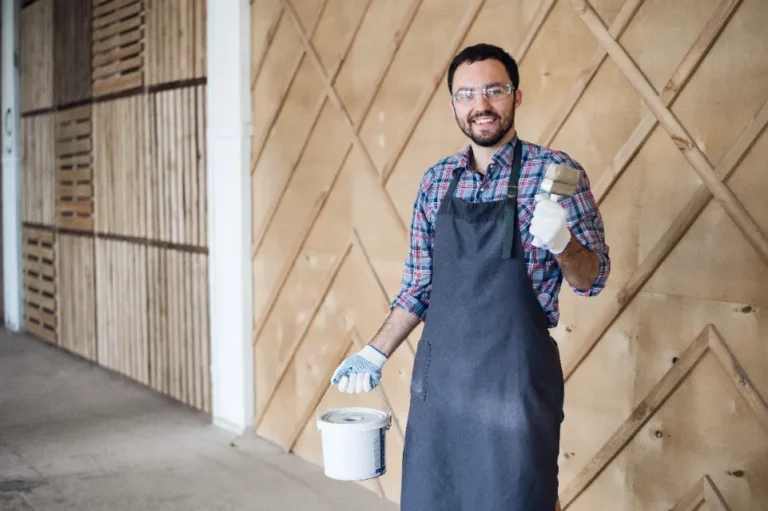 Local painter holding paintbrush and paint can, smiling.